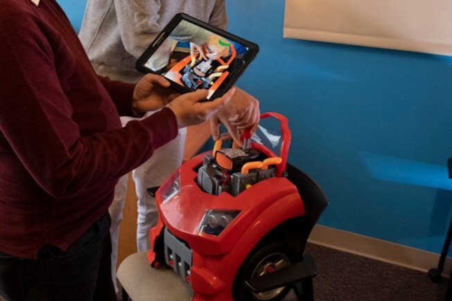 Woman hold tablet up to engine model.