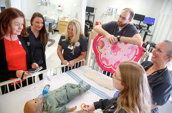 Nursing students who received the Pat Walker scholarship pose in groups and demonstrate the technological capabilities of the robotic SIM Lab mannequins. Photo by Benjamin Krain