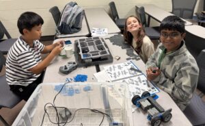 A trio of young campers are working on building a robot together.